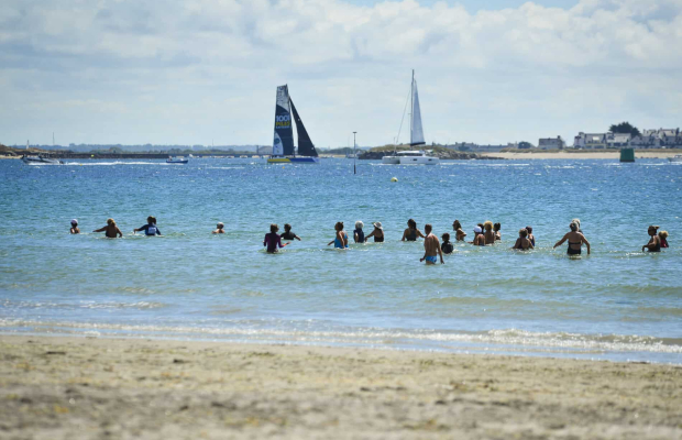 Larmor-Plage, marche aquatique en groupe sur la plage de Toulhars et voiliers au loin.