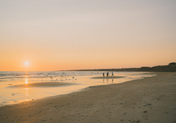 Jeunes courant à la plage et coucher de soleil sur la plage du Loch à Guidel-Plages.