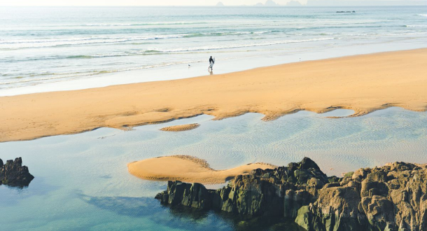 Surfeur sur la plage de la Palue et vue sur la Pointe du Raz sur la presqu'île de Crozon (Finistère)