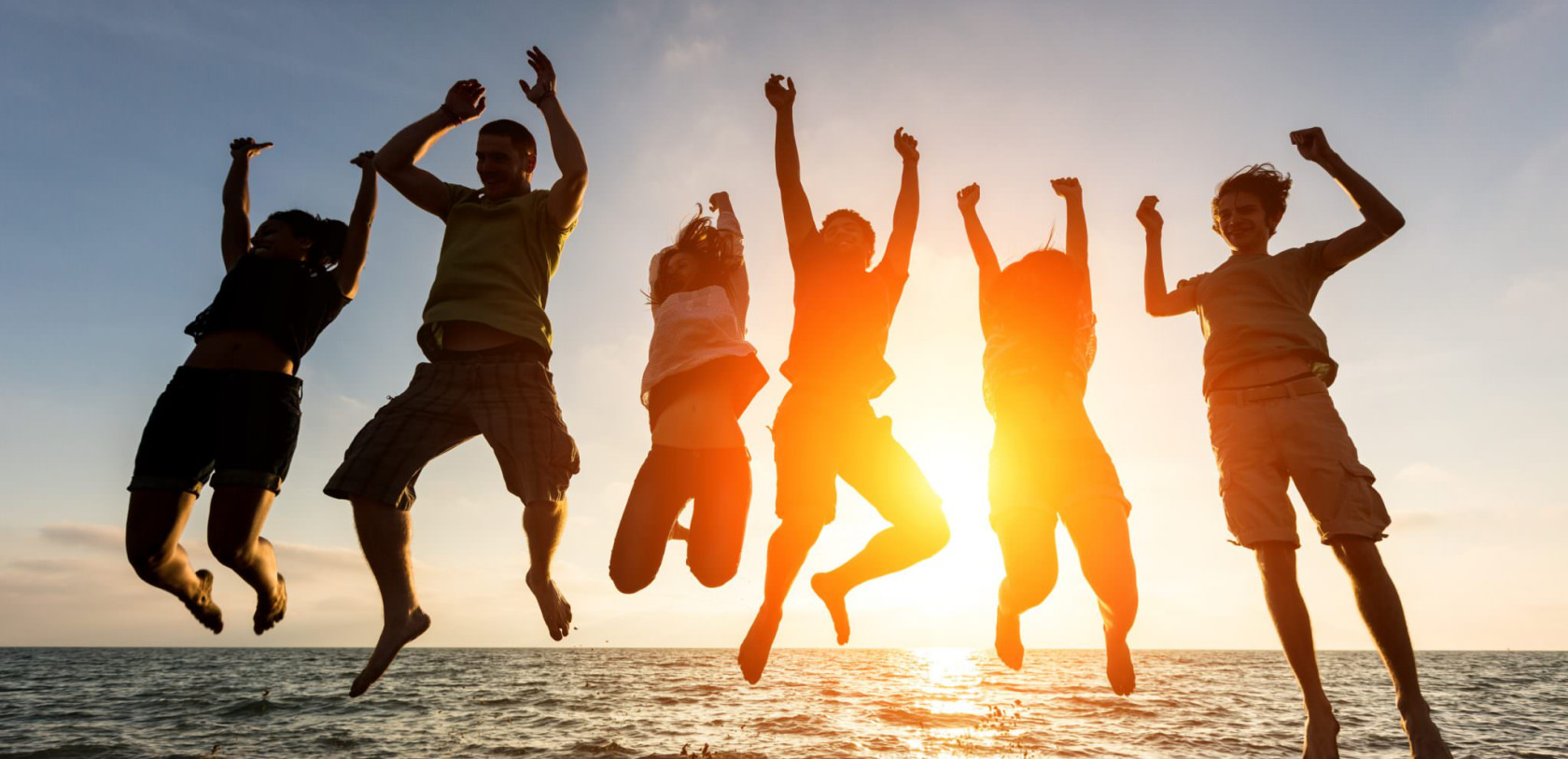 Saut groupé devant la mer au coucher du soleil