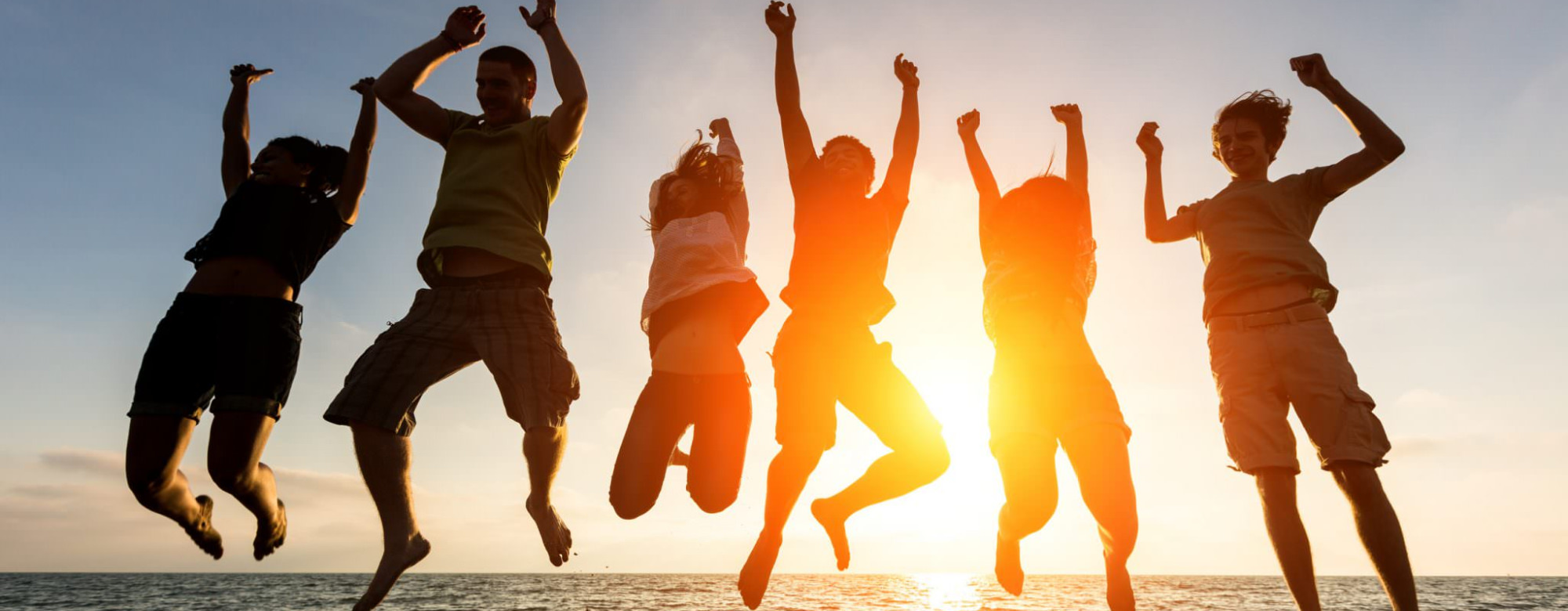 Saut groupé devant la mer au coucher du soleil